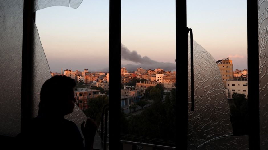 A Palestinian child watches as smoke billows on the horizon after an Israeli air strike in Gaza City on October 13, 2023. 