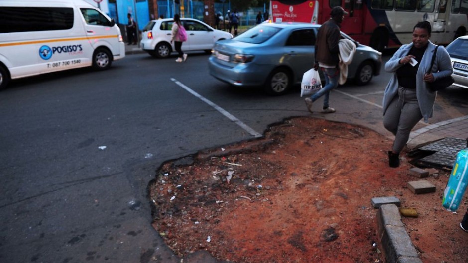 Traffic and pedestrians navigate a hole in the road in Johannesburg. Leon Sadiki/Bloomberg via Getty Images