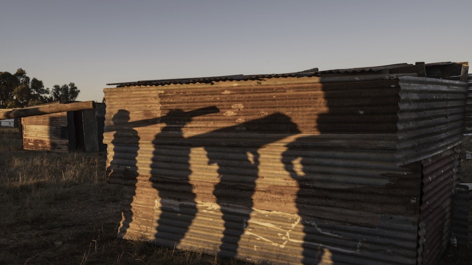 Shadows of would-be residents carrying construction materials are cast on a shack in the area where structures have been erected. AFP/Marco Longari