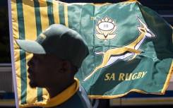 A hawker is seen in front of a South African Rugby team flag at an intersection in Melrose. AFP/Emmanuel Croset