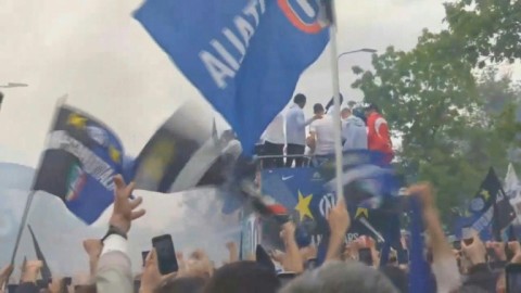 Inter Milan players and staff ride on open-top buses, surrounded by clouds of blue smoke and a crowd of supporters after the club's first home game since clinching the Serie A title.