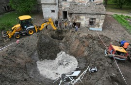 Utility workers operate next to a crater in the courtyard of a hospital in Kharkiv