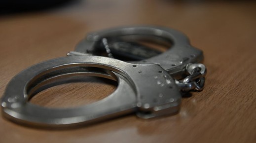 File: A set of handcuffs lying on a desk. Wikimedia Commons/Airman 1st Class Gustavo Castillo