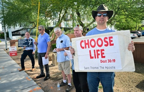 Matthew Engelthaler stands with a group of men from a local Catholic Church who gather "not to protest but to pray" for those arriving at Camelback Family Planning, an abortion clinic in Phoenix, Arizona 