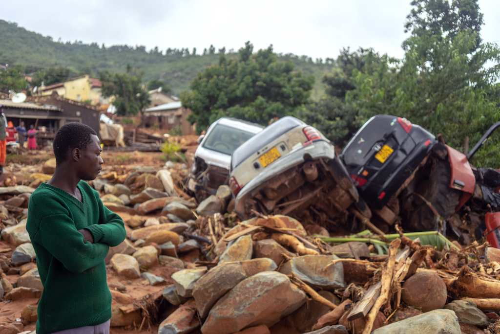 A man stands next to the wreckage a vehicles washed away in Chimanimani, eastern Zimbabwe, after the area was hit by the cyclone Idai. 