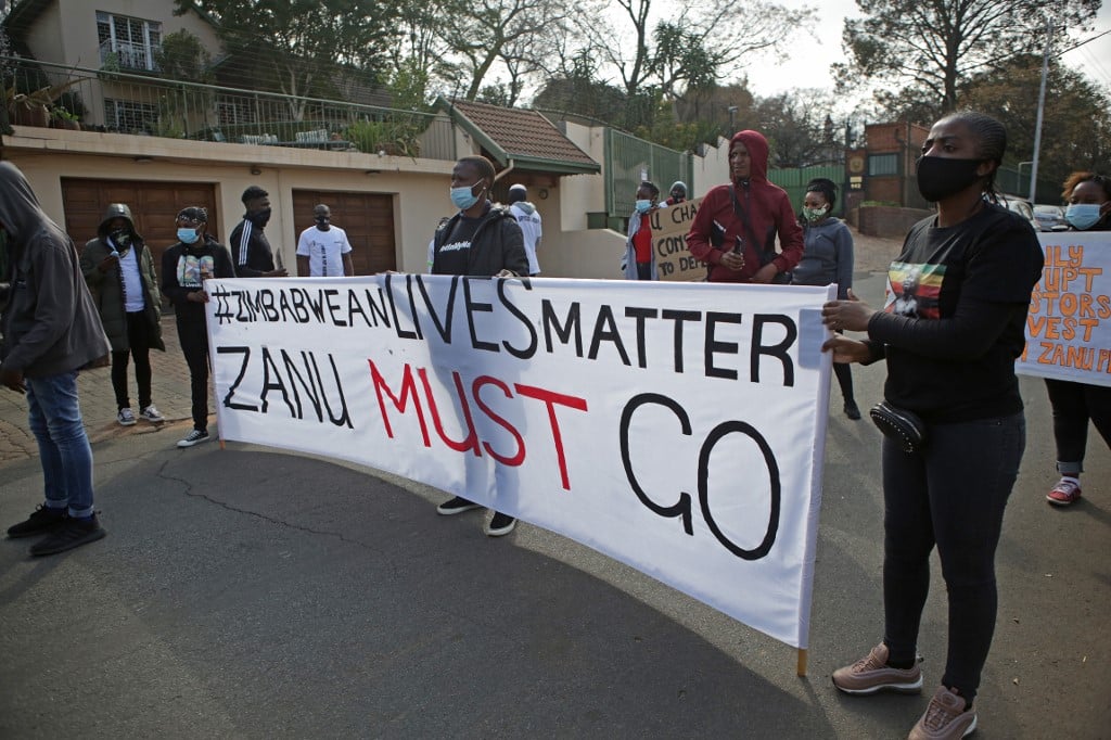 Protestors hold up plackards against the government of Zimbabwe's alleged state corruption, media freedom and the deteriorating economy outside the Zimbabwean Embassy in Pretoria on August 7, 2020.
