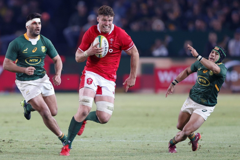 Wales lock Will Rowlands (C) races past South Africa backs Damien de Allende (L) and Cheslin Kolbe (R) during a Test in Pretoria on July 2, 2022.