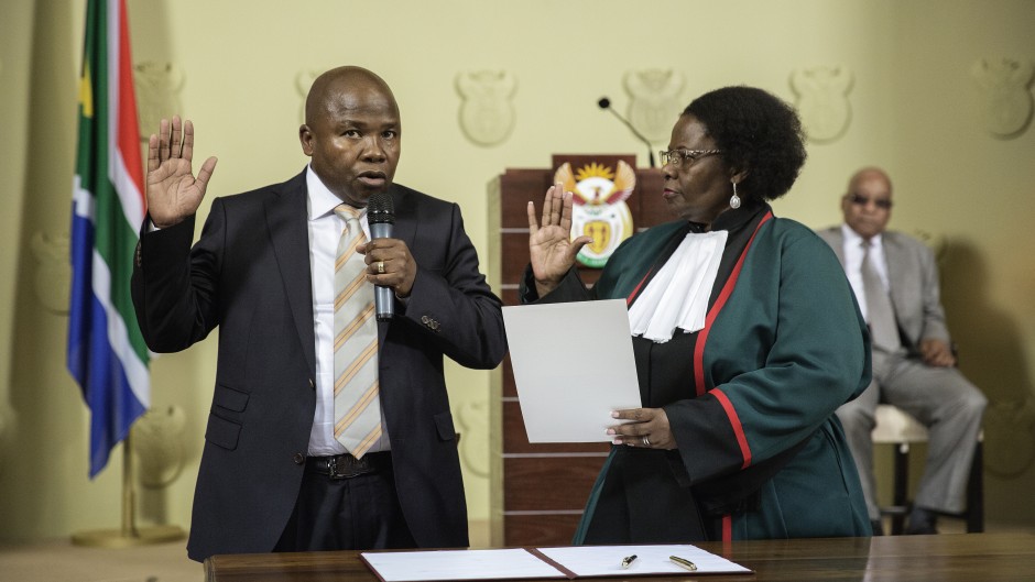 File: Des van Rooyen (L) raises his hand as he is sworn-in by Justice minister Sisi Khampepe as the new South African Finance Minister on December 10, 2015 at Union Builidngs in Pretoria, South Africa. 