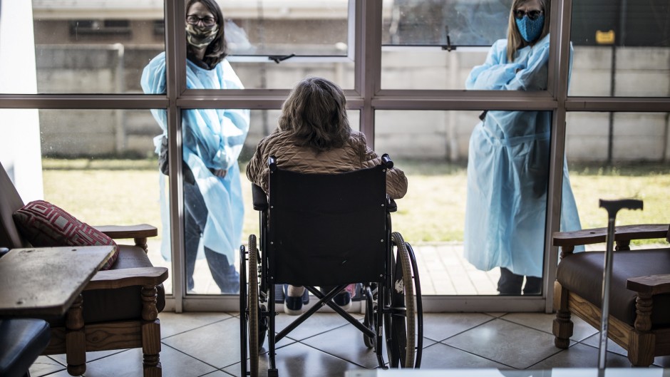 Relatives chat through a window to a wheelchair-bound woman at an old age home in Johannesburg. Under Level 2 lockdown regulations, restrictions on family and social visits have been lifted.
