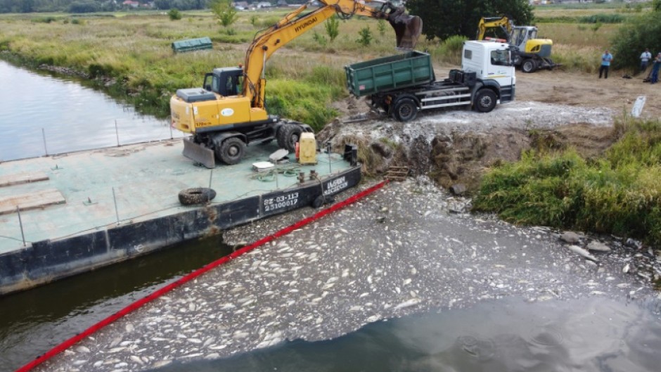 A floating dam is used to encircle dead fish on the Oder River and an escavator to remove them on August 15, 2022 after mass fish deaths taht Polish authorities say are due to toxic algae