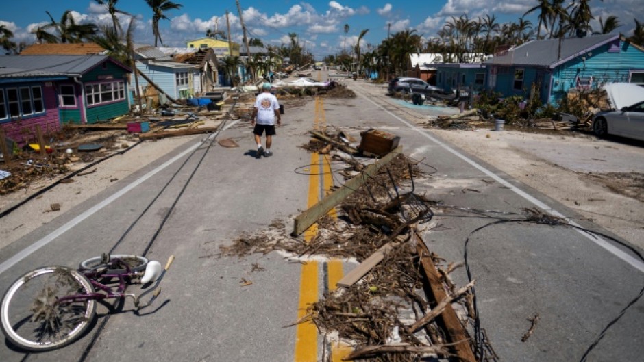 A man walks pass debris scattered on Pine Island Road in the aftermath of Hurricane Ian in Matlacha, Florida 