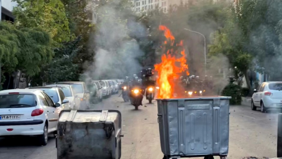 Street bins burn during clashes in Tehran