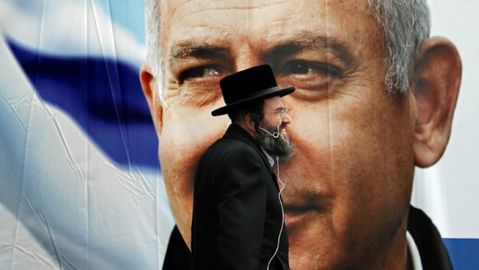 An Ultra Orthodox Jewish man walks past an electoral billboard bearing a portrait of Israel's then prime minister Benjamin Netanyahu back in 2019 -- one of the many national polls Israelis have voted in during recent years
