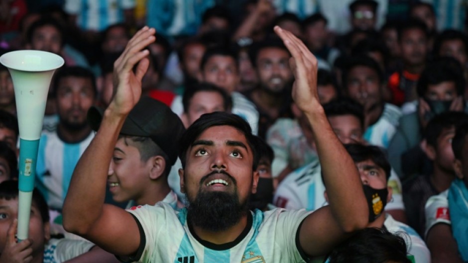 Football fans react as they watch the World Cup match between Poland and Argentina on a big screen in Dhaka