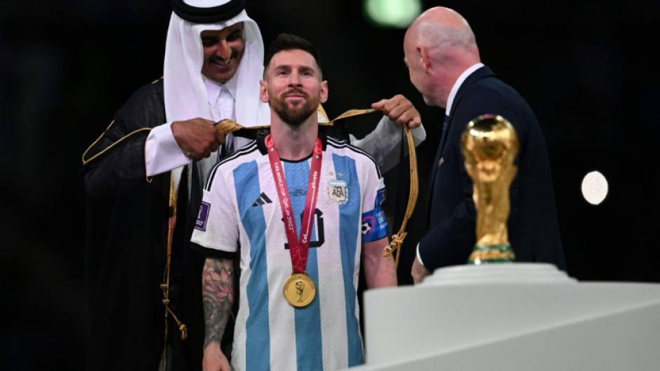 Honour: Qatar's Emir Sheikh Tamim bin Hamad al-Thani presents Lionel Messi with a traditional cloak after winning the World Cup
