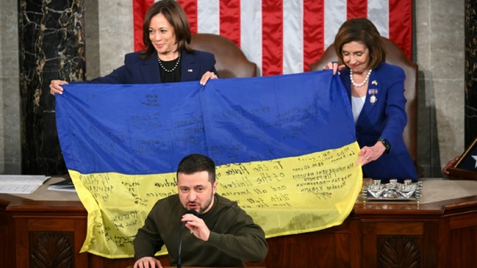House Speaker Nancy Pelosi, left, and Vice President Kamala Harris hold a Ukrainian battle flag donated to Congress by Zelensky, front