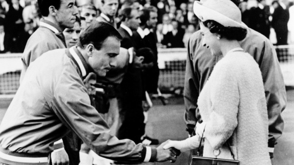 George Cohen, with teammate goalkeeper Gordon Banks hehind,  him, bows as he shakes hand with Queen Elizabeth II at Wembley stadium in London before the start of the World Cup