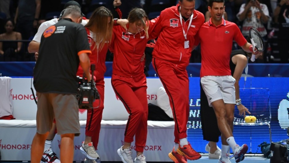 In perfect step: Novak Djokovic (right) celebrates with his teammates after victory in Dubai on Friday