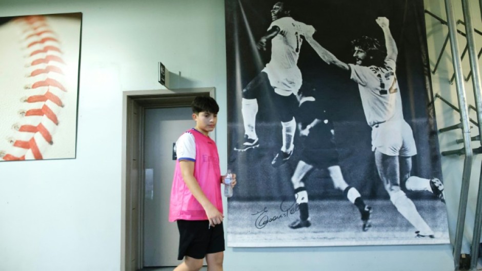 A young athlete walks past a poster showing Pele and defender Robert "Bobby" Smith at a sports academy now run by Smith in New Jersey 