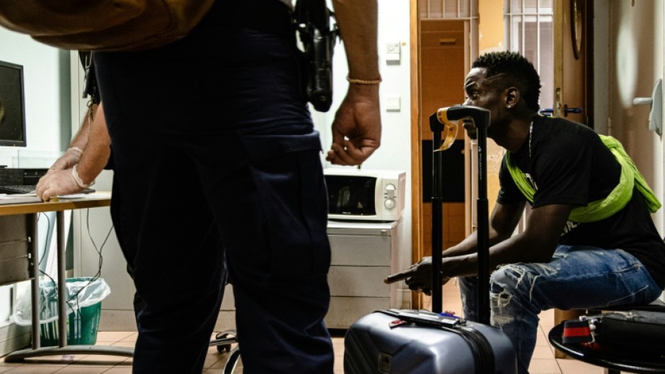 Border force police search a passenger boarding a flight from Cayenne, French Guiana