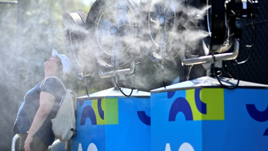 A woman cools off in front of mist cooling fans at the Australian Open