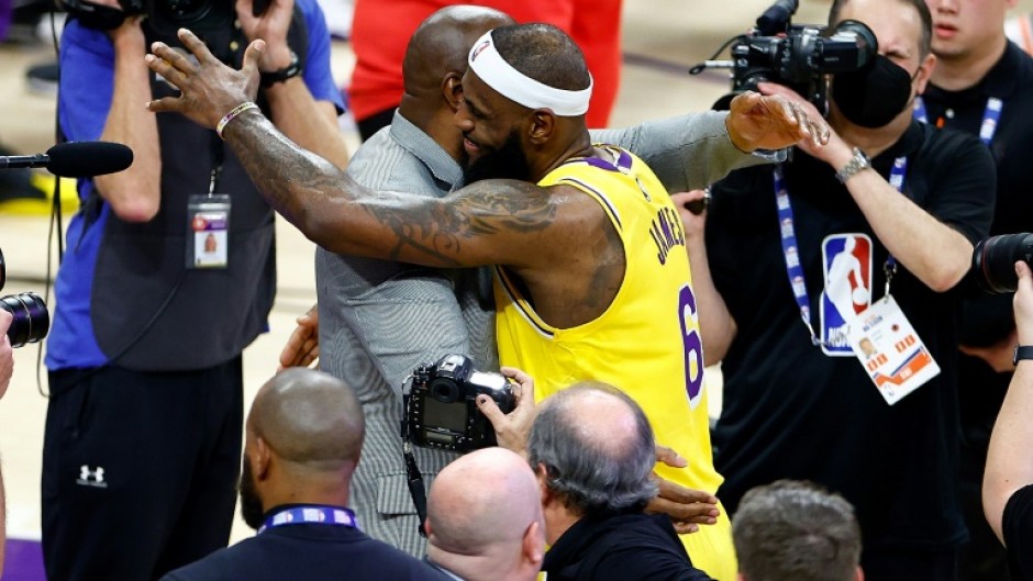 LeBron James, at center right, celebrates with retired Los Angeles Lakers legend Magic Johnson, center left, after James overtook Kareem Abdul-Jabbar to become the NBA's all-time leading scorer