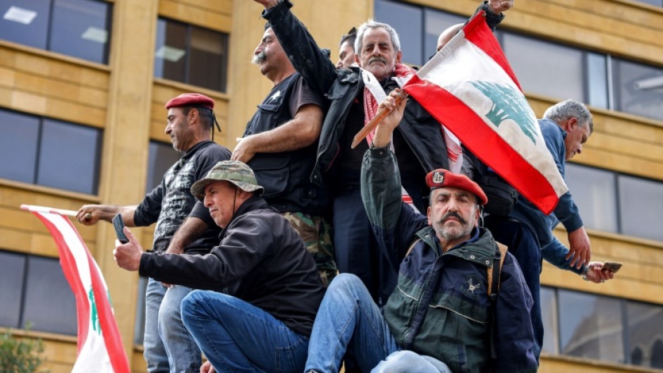 Protesters wave Lebanon's flag during a demonstration by retired army and security forces veterans on Wednesday, demanding inflation-adjustments to their pensions