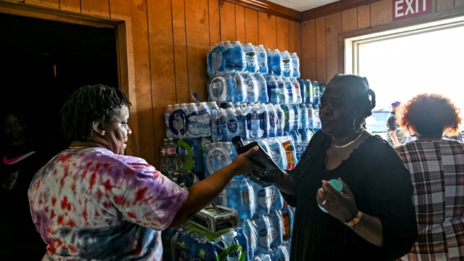A volunteer carries jugs of water and supplies from a makeshift clinic and relief center in Rolling Fork, Mississippi