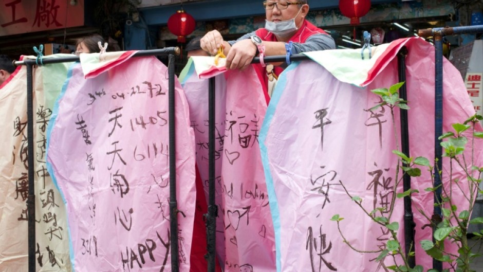 A vendor hangs sky lanterns with messages of peace written on them at the Shihfeng train station in New Taipei City 