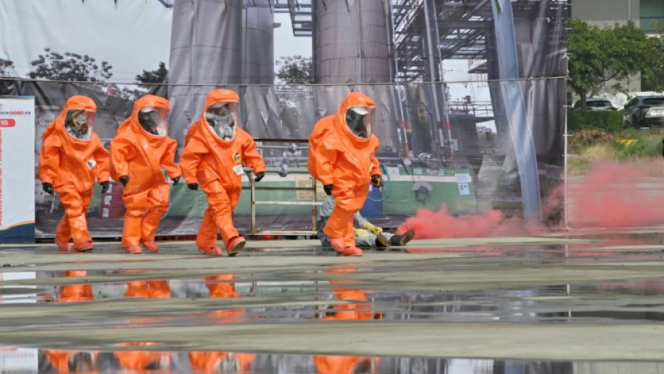 Rescuers in protective equipments walk past a mock collapsed nuclear power plant during a civilian drill while imitating a Chinese attack in Taichung in April 2023