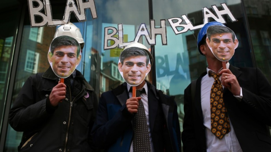 Protesters hold up masks of Britain's Prime Minister Rishi Sunak in London