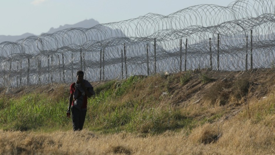 A migrant walks along the banks of the Rio Grande river to surrender to US border agents from El Paso, Texas