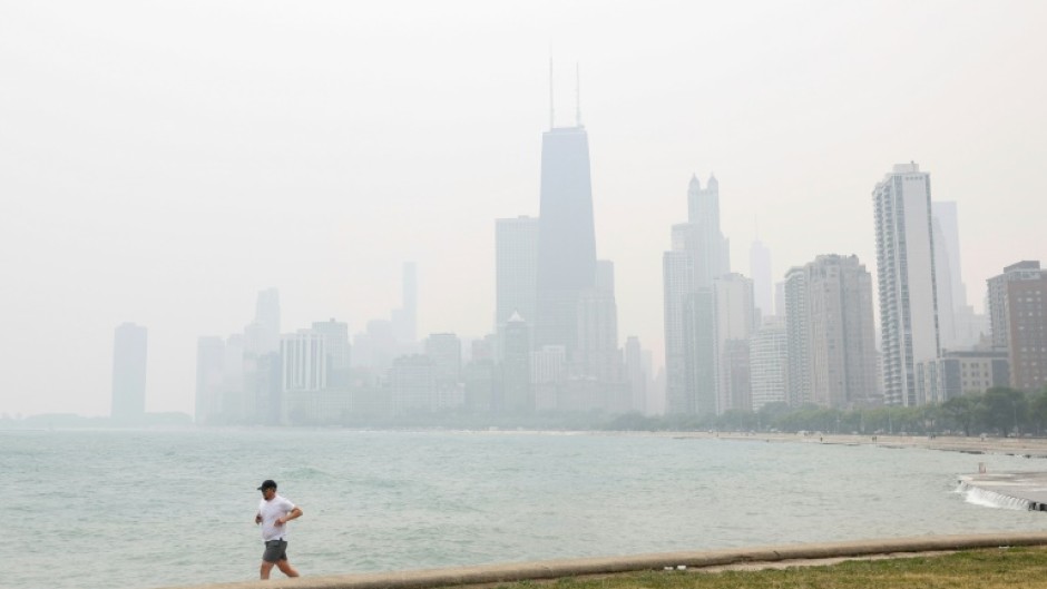 A jogger runs along the shoreline of Lake Michigan with heavy smoke from the Canadian wildfires covering the city of Chicago in a thick haze