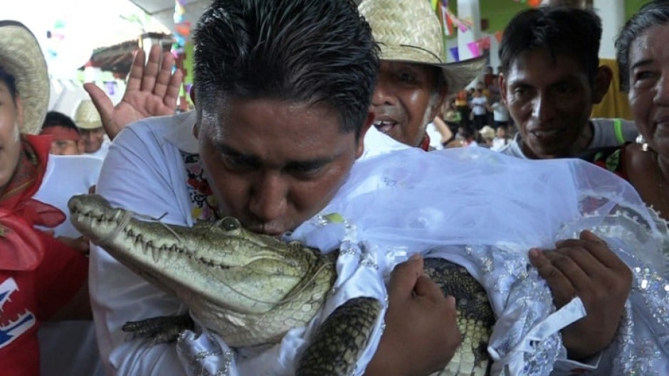 The mayor of San Pedro Huamelula, Victor Hugo Sosa, kisses a female caiman as part of a marriage ritual on June 30, 2023
