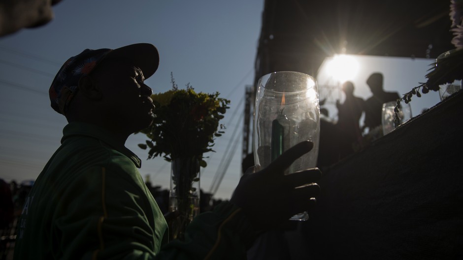 A mine worker holds a candle during a ceremony marking the third anniversary of the Marikana massacre of 34 striking platinum miners, near Rustenburg, on August 16, 2015.