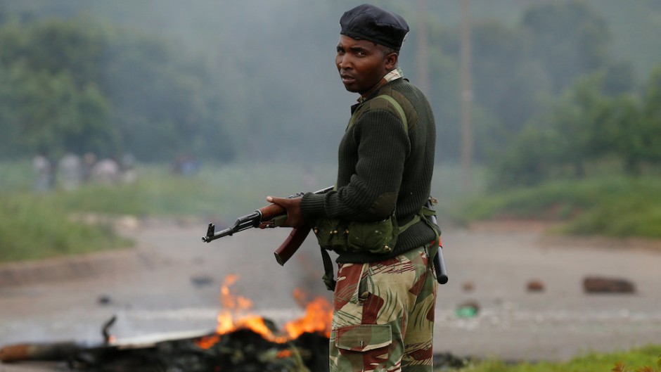A soldier stands before a burning barricade during protests in Harare, Zimbabwe.
