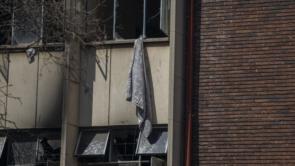 A blanket hanging out of a window that residents used to climb out of the building at the scene of a fire in Johannesburg. AFP/Michele Spatari 