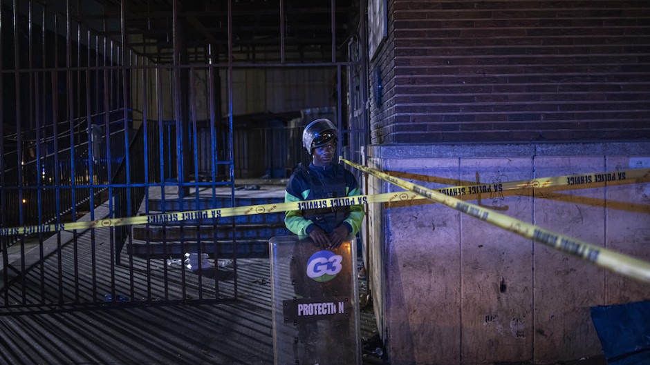 A private security guard stands at the scene of a fire in Johannesburg. AFP/Michele Spatari