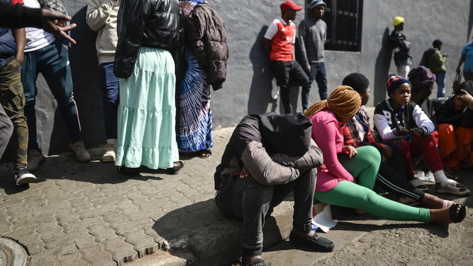 Residents, relatives of victims and members of the public gather at the site of a burned apartment block in Johannesburg. AFP/Luca Sola