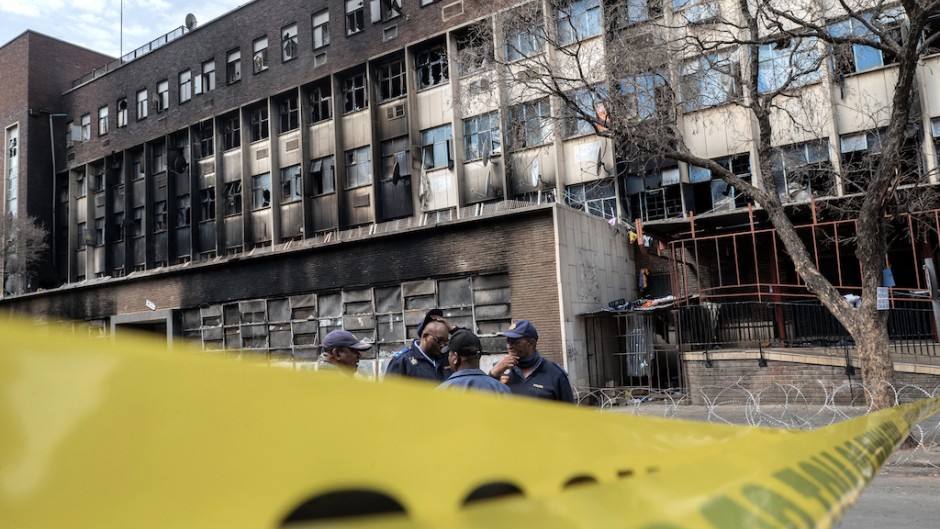 Police officers stand at the scene of the Joburg building fire. AFP/Luca Sola