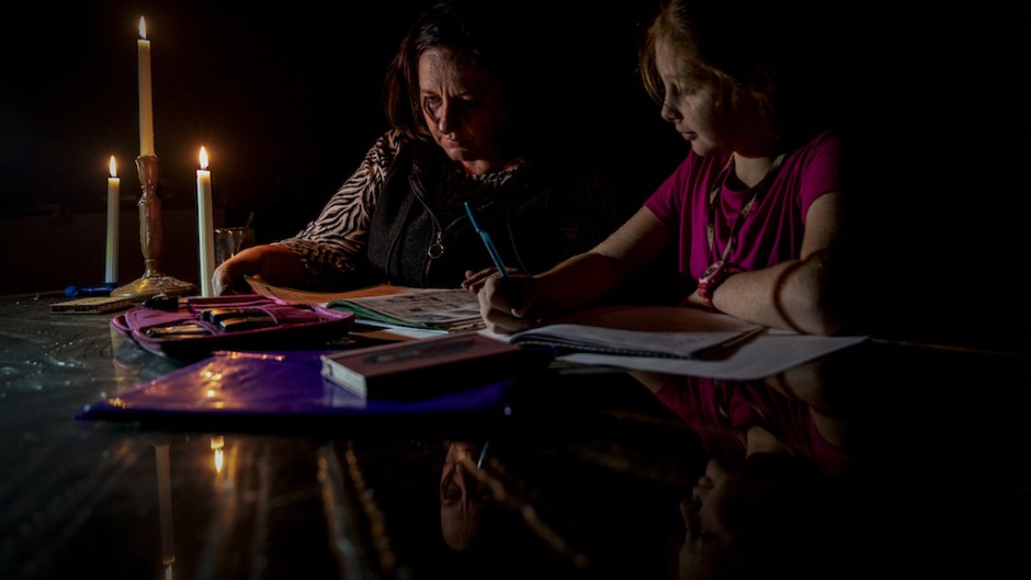 File: Marina Van Biljon (L) and her daughter, Nika, do homework during load-shedding in Frankfort. AFP/Shiraaz Mohamed