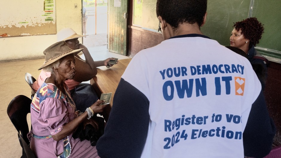 Two women give their identity documents to Electoral Commission of South Africa (IEC) officials to be registered as voters during the nationwide voter registration campaign ahead of the 2024 general elections at a voting station in Soweto on November 18, 2023.