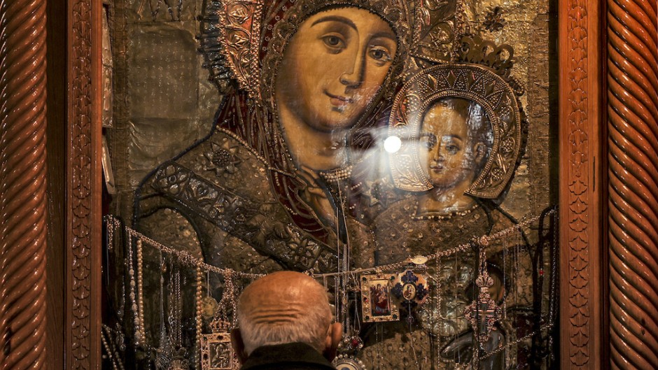 A Christian worshipper prays before the Bethlehemitissa icon of the Virgin Mary with the Child Jesus. AFP/Hazem Bader