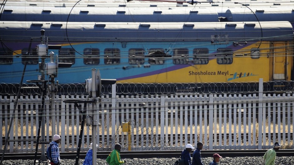 File: People walk on the railway track near a Shosholoza Meyl train. AFP/Gianluigi Guercia