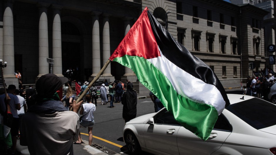 A man holds a Palestinian flag as they take part in a pro-Palestinian demonstration outside the High Court in Cape Town. AFP/Rodger Bosch