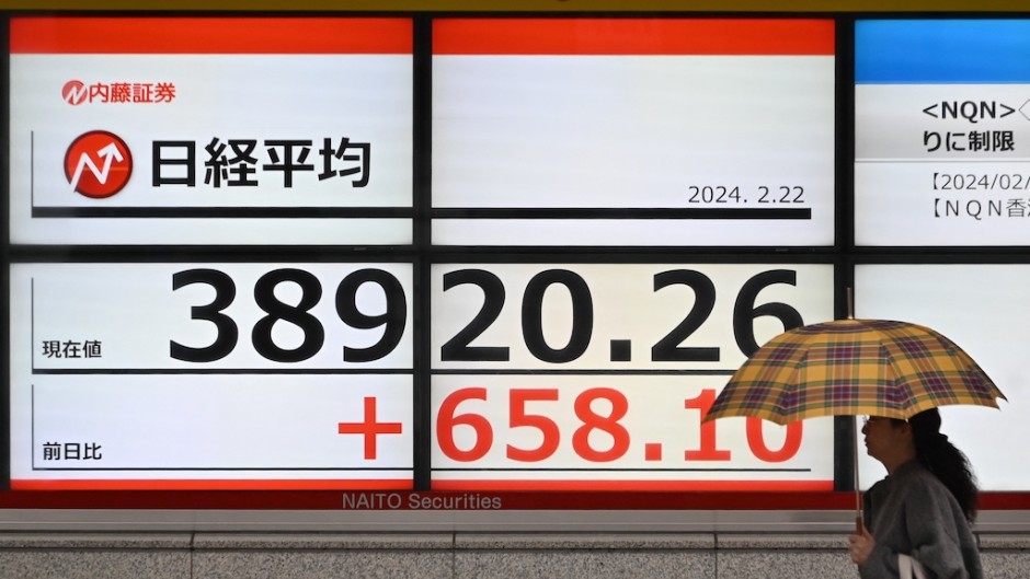 A woman walks in front of an electronic quotation board displaying share price of the Tokyo Stock Exchange. AFP/Kazuhiro Nogi