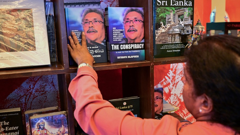 A woman looks at the copies of the 'The Conspiracy' book written by toppled Sri Lankan president Gotabaya Rajapaksa. AFP/Ishara S Kodikara