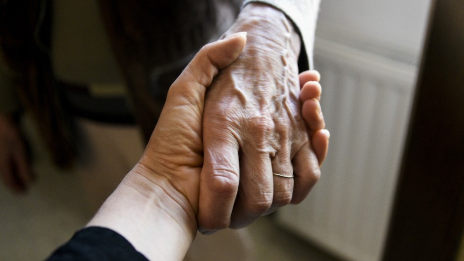 A young woman holds the hand of an old woman. AFP/Magali Cohen/Hans Lucas via AFP