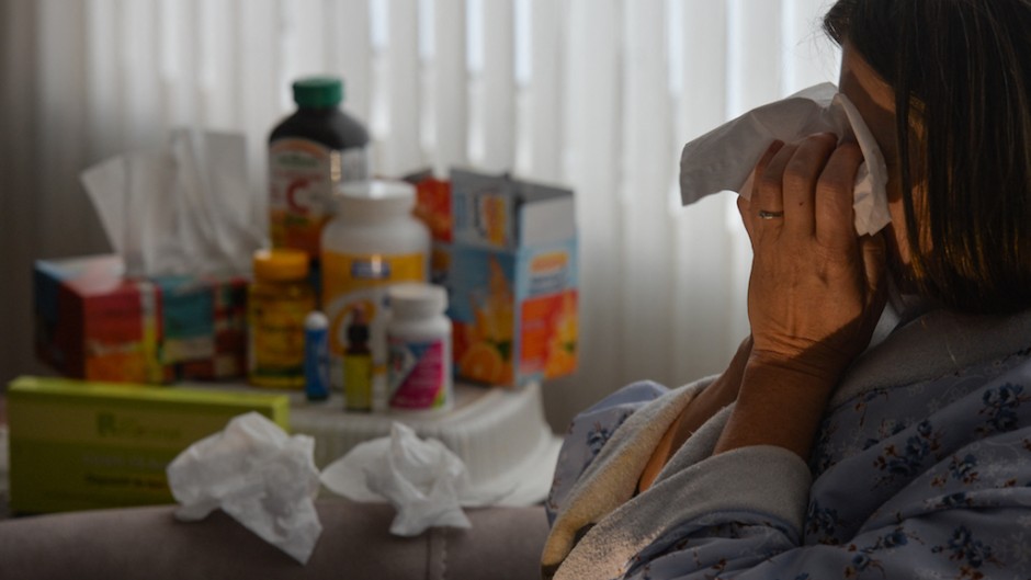 File: A woman lying in an armchair, coughing and covering her mouth with tissues. Artur Widak/NurPhoto via AFP