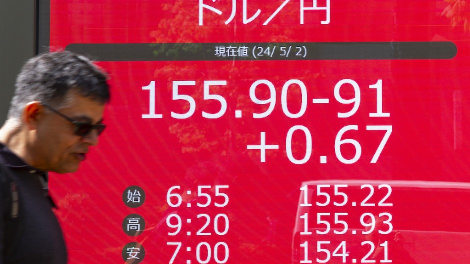 A man walks in front of an electronic board displaying the exchange rate for the Japanese yen against the US dollar. AFP/Kazuhiro Nogi